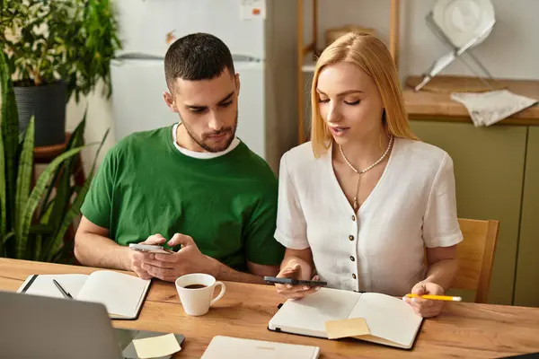 A couple at a wooden table is focused on their phones and notes, surrounded by plants. — Stock Photo