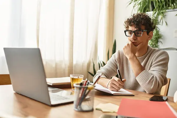 Un uomo giovane ed elegante medita idee mentre prende appunti in un accogliente spazio di lavoro domestico pieno di piante. — Foto stock