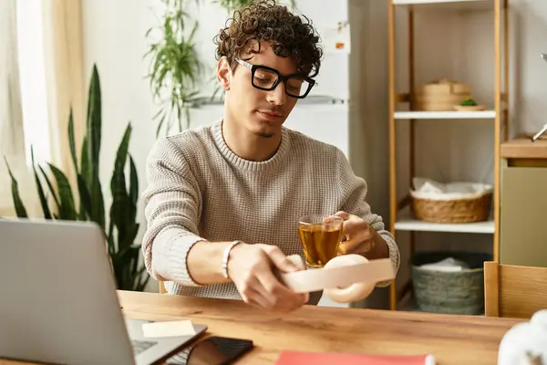 Un bel giovane uomo in bicchieri sorseggia tè nel suo elegante spazio di lavoro, concentrandosi sul suo compito.. — Stock Photo