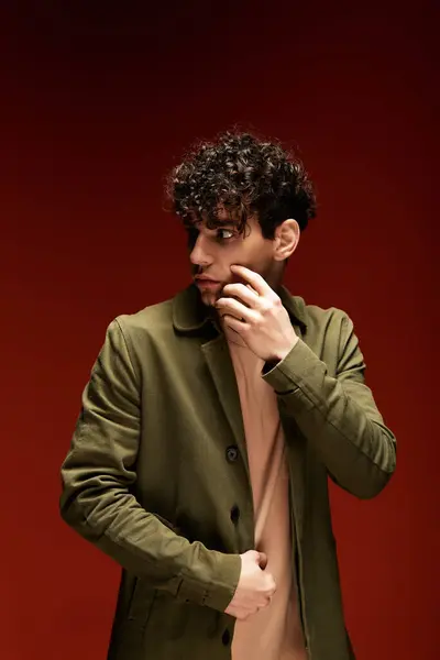 A handsome man with curly hair showcases a fashionable outfit while striking a thoughtful pose. — Stock Photo