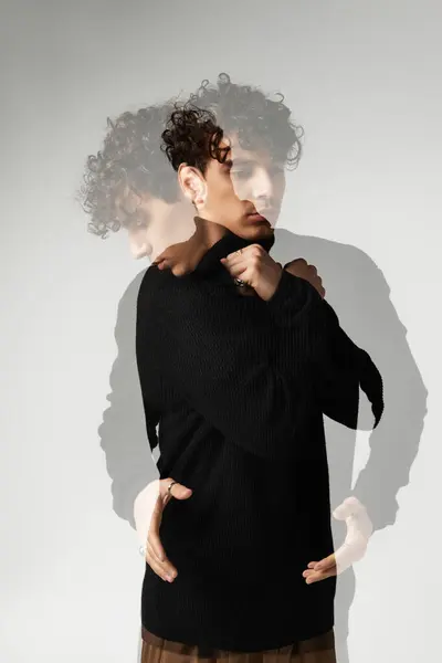 A handsome young man in a black sweater exudes charm and style amidst a creative backdrop. — Stock Photo