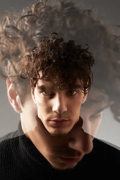 Un giovane elegante con i capelli ricci guarda, trasudando fiducia e introspezione. — Foto stock