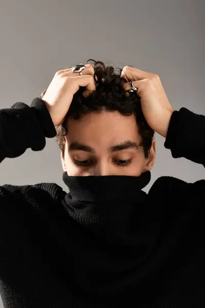 A stylish young man with curly hair shows a range of emotions while wearing a black sweater. — Stock Photo