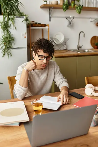 Handsome young man wearing glasses engages in deep concentration while taking notes in his notebook. — Stock Photo