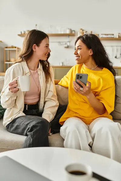 Two women share a warm connection while sitting on a sofa in their inviting living room. — Stock Photo
