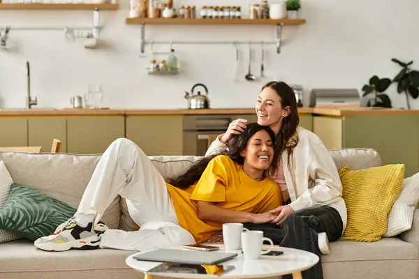 Two women share joyful moments together on a cozy couch, exuding tenderness. — Stock Photo