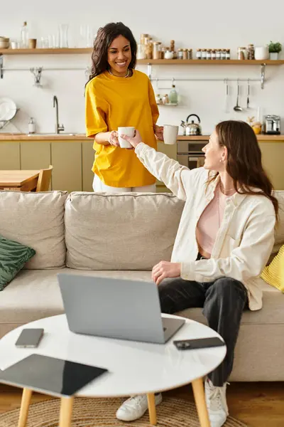 Two women enjoy each others company at home while sharing drinks and laughter together. — Stock Photo
