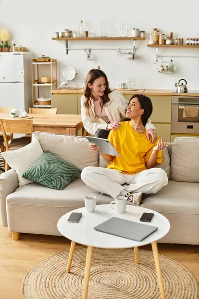 Two women enjoy a joyful chat on a sofa in their cozy, beautifully arranged home. — Stock Photo