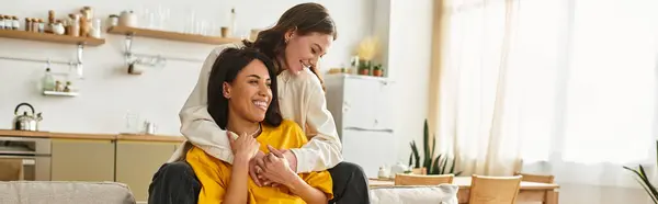 Two women embrace happily while enjoying each others company in their warm home. — Stock Photo