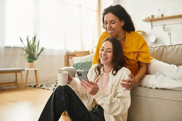 Two women enjoy each others company while smiling and sharing a moment with a smartphone. — Stock Photo