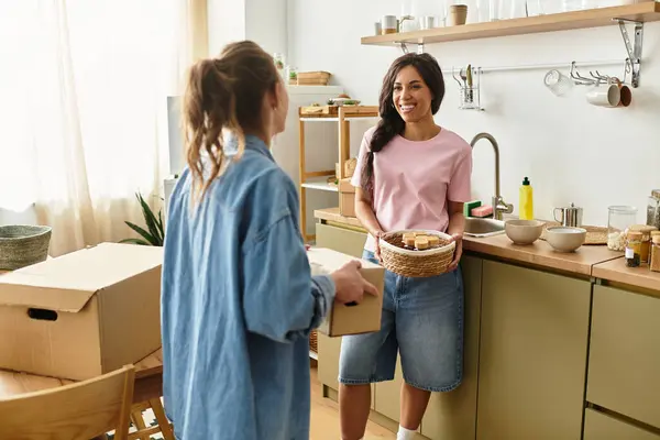 In a warm home setting, two women unpack boxes, sharing joy and laughter in their new space. — Stock Photo