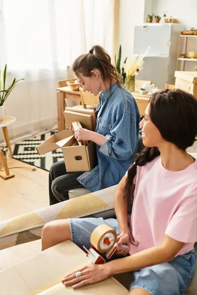 Zwei Frauen teilen einen herzlichen Moment beim Auspacken von Kartons in ihrem gemütlichen Wohnzimmer. — Stockfoto