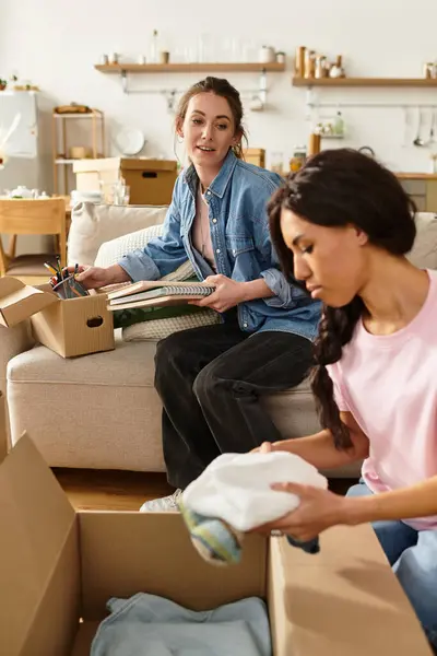 Two women share a tender moment while unpacking boxes filled with their belongings at home. — Stock Photo