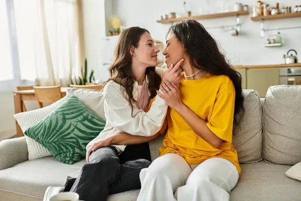 Duas mulheres compartilham um abraço terno e risos alegres enquanto relaxam em seu brilhante espaço de vida. — Fotografia de Stock