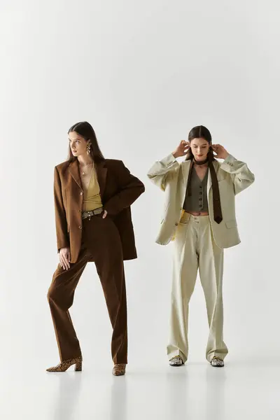 Twin sisters elegantly pose, highlighting their distinct styles in a bright, modern space. — Stock Photo