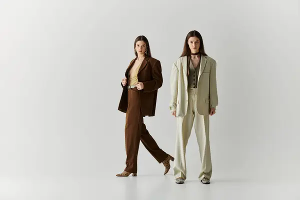 Twin sisters radiate elegance in coordinating outfits while standing confidently in a chic studio. — Stock Photo