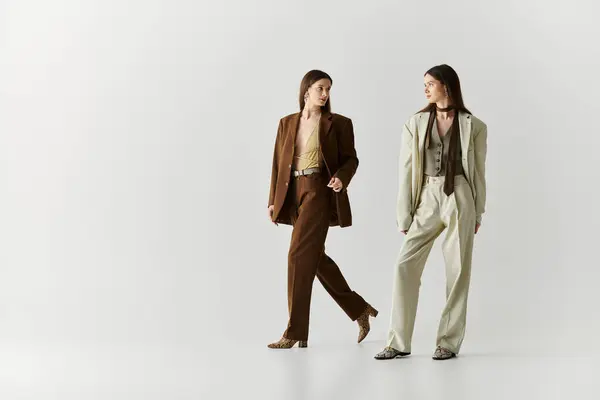 Two elegant twin sisters express their distinct styles while interacting playfully indoors. — Stock Photo