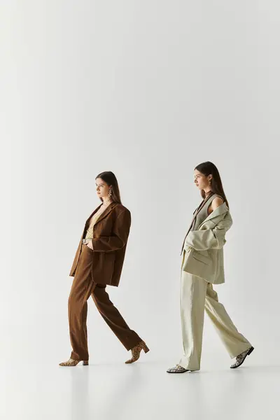 Two beautiful young twin sisters showcase their unique styles while bonding in elegant attire. — Stock Photo