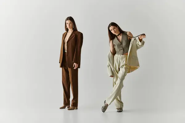 Twin sisters express their bond through stylish outfits and confident poses in a chic backdrop. — Stock Photo
