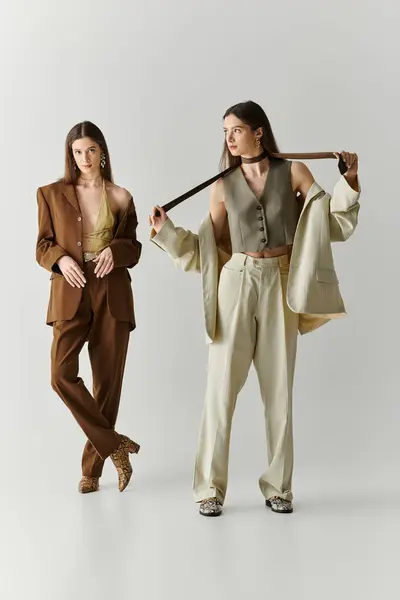 Twin sisters elegantly pose in trendy outfits, exuding confidence and style while bonding together. — Stock Photo