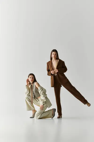 Zwillingsschwestern versprühen Charme und Stil, während sie anmutig in trendigen Outfits posieren. — Stockfoto