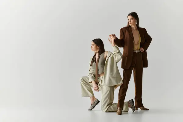 Twin sisters express their bond and individual styles while posing creatively in a modern studio. — Stock Photo