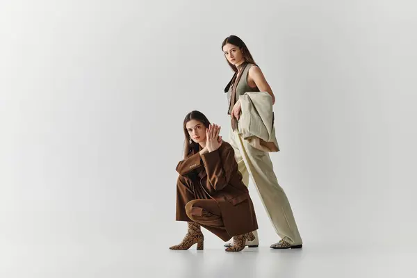Twin sisters strike a fashionable pose in a chic studio, highlighting their unique styles. — Stock Photo