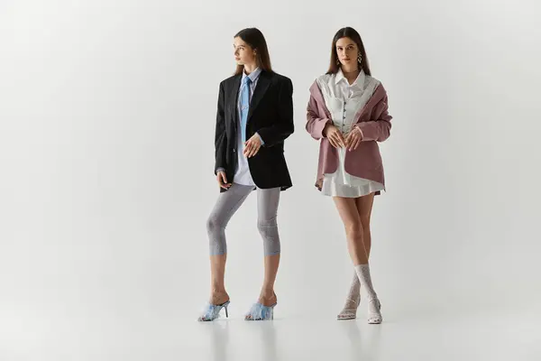 Twin sisters express their individual styles with confidence and elegance in a casual setup. — Stock Photo