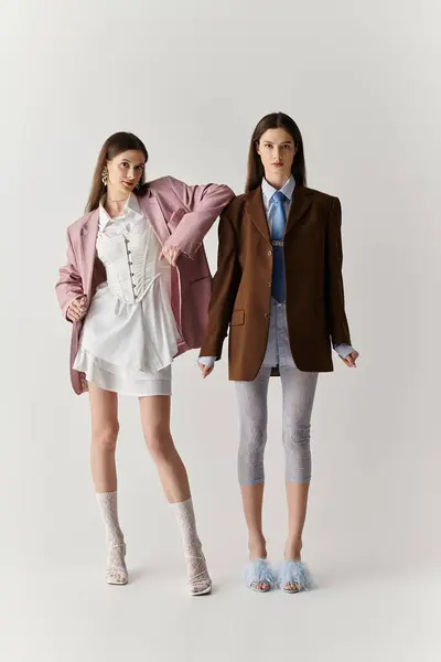 Irmãs gêmeas posar graciosamente em roupas elegantes, mostrando seu vínculo único e individualidade. — Fotografia de Stock