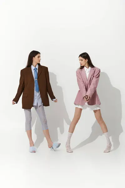 Sœurs jumelles expriment leurs personnalités vibrantes à travers des choix de mode contrastés et pose. — Photo de stock