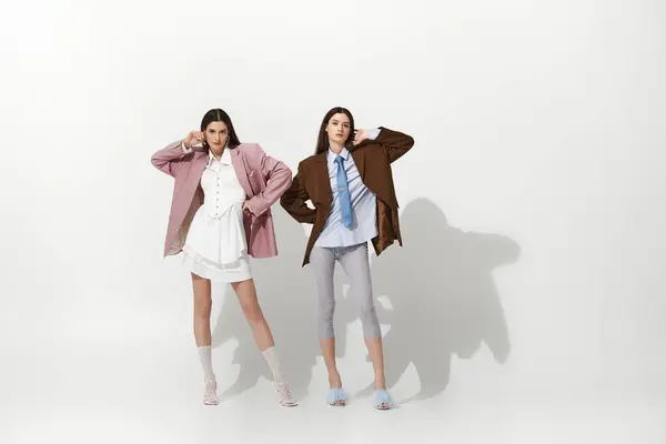 Two beautiful twin sisters showcase their trendy outfits while posing playfully together. — Stock Photo