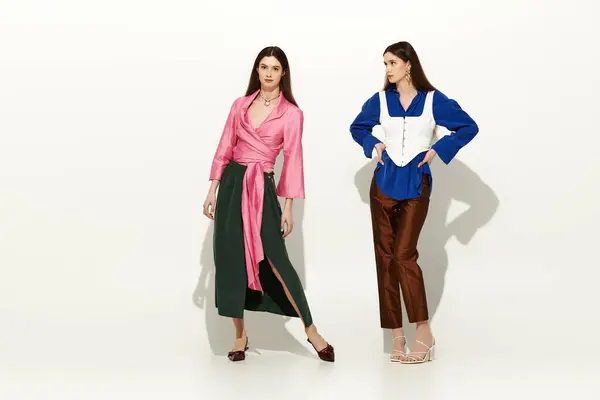 Twin sorelle irradiano bellezza e stile in abiti chic su uno sfondo vibrante. — Foto stock