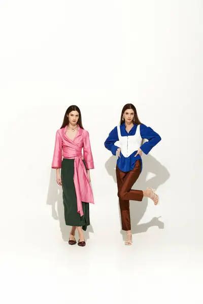 Twin sisters exude elegance and camaraderie as they strike poses in trendy outfits. — Stock Photo