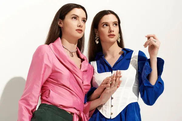 Gemelle brillano in abiti vibranti, legame sopra la moda in un ambiente minimalista chic. — Foto stock