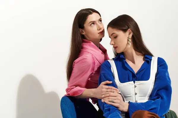 Deux charmantes sœurs montrent leur lien dans des tenues vibrantes dans un cadre élégant. — Photo de stock