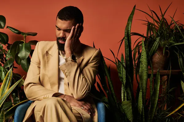 A well dressed young man enjoys a moment of reflection among vibrant plants in summers warmth. — Stock Photo