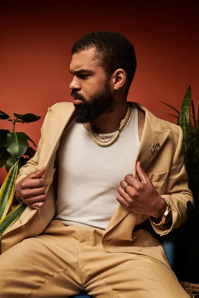 Guapo joven muestra el estilo de verano mientras está sentado sobre un telón de fondo de tonos cálidos. - foto de stock