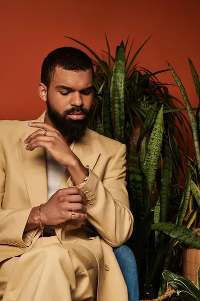 Dressed elegantly, a handsome man showcases summer fashion amidst vibrant greenery indoors. — Stock Photo