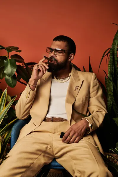 Hombre en traje de verano elegante se relaja con un cigarro, rodeado de plantas vibrantes para un ambiente elegante. — Stock Photo
