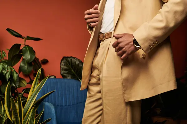 A young man showcases summer fashion in a stylish light suit amidst lush plants indoors. — Stock Photo