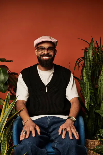 Young man with a friendly smile enjoys a relaxed moment in a trendy summer look amidst plants. — Stock Photo