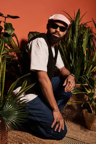 Bonito jovem mostra a moda de verão enquanto posando em meio a plantas verdes exuberantes. — Fotografia de Stock