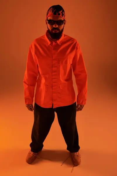 Ein modischer junger Mann steht selbstbewusst in leuchtend orangefarbener Kleidung und präsentiert sommerlichen Stil. — Stockfoto