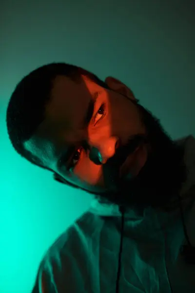 Un jeune homme présente la mode estivale avec une expression élégante sous un éclairage coloré. — Photo de stock