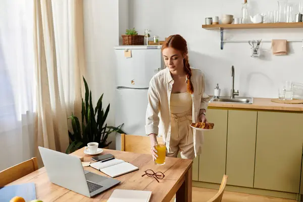 A woman with red hair makes a refreshing drink in a warm, bright kitchen. — Stock Photo