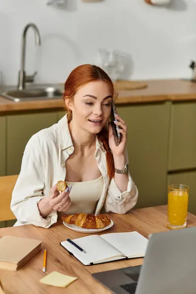 Bright morning in a modern kitchen with a cheerful woman eating breakfast and chatting on her phone. — Stock Photo