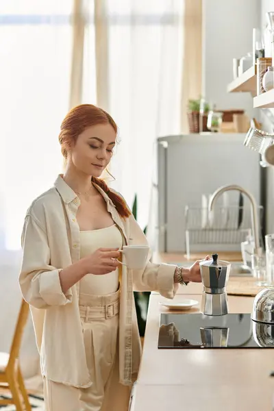 A beautiful woman with red hair enjoys brewing a fresh cup of coffee in her warm, inviting kitchen. — Stock Photo