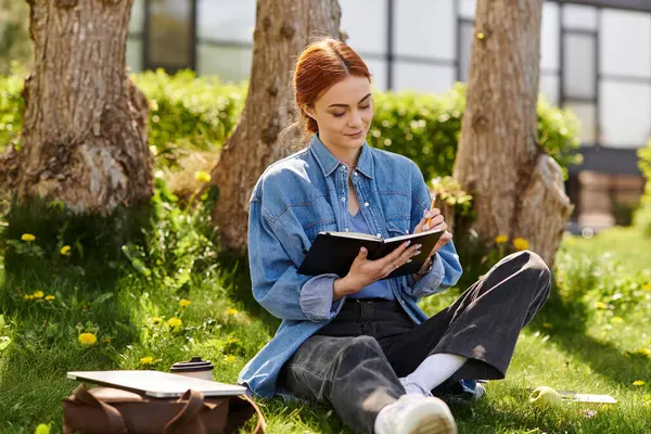 A beautiful red haired woman enjoys a calm afternoon writing in her notebook surrounded by greenery. — Stock Photo