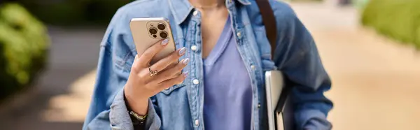 Donna dai capelli rossi cammina con fiducia su un sentiero soleggiato durante l'utilizzo del suo smartphone. — Foto stock