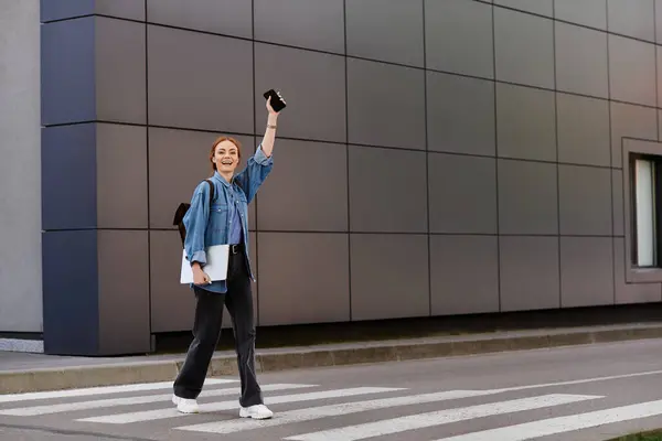 Bright smile of a red haired woman as she waves cheerfully while walking across the street. — Stock Photo